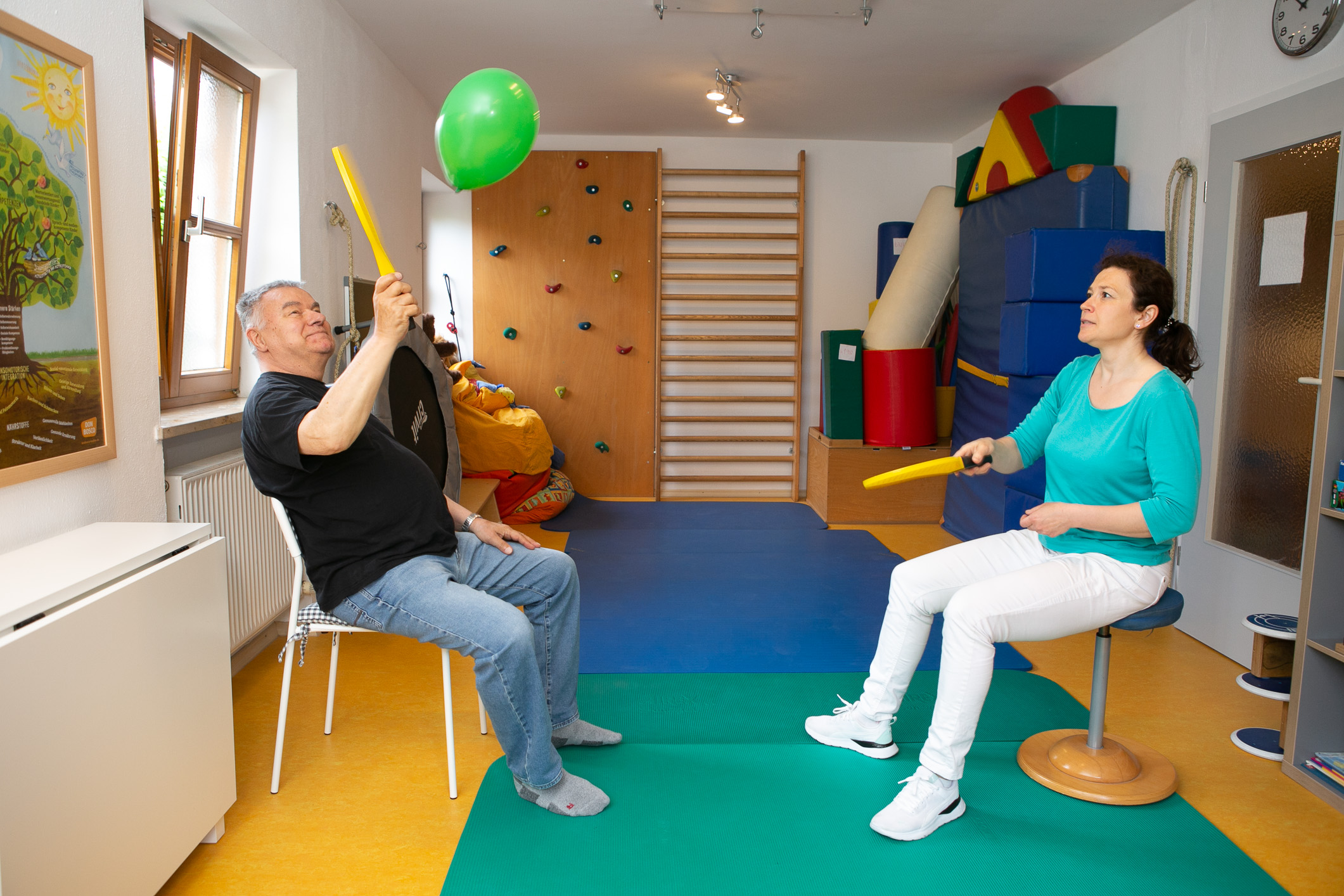 Ein älterer Mann spielt mit der Therapeutin Luftballon-Tennis